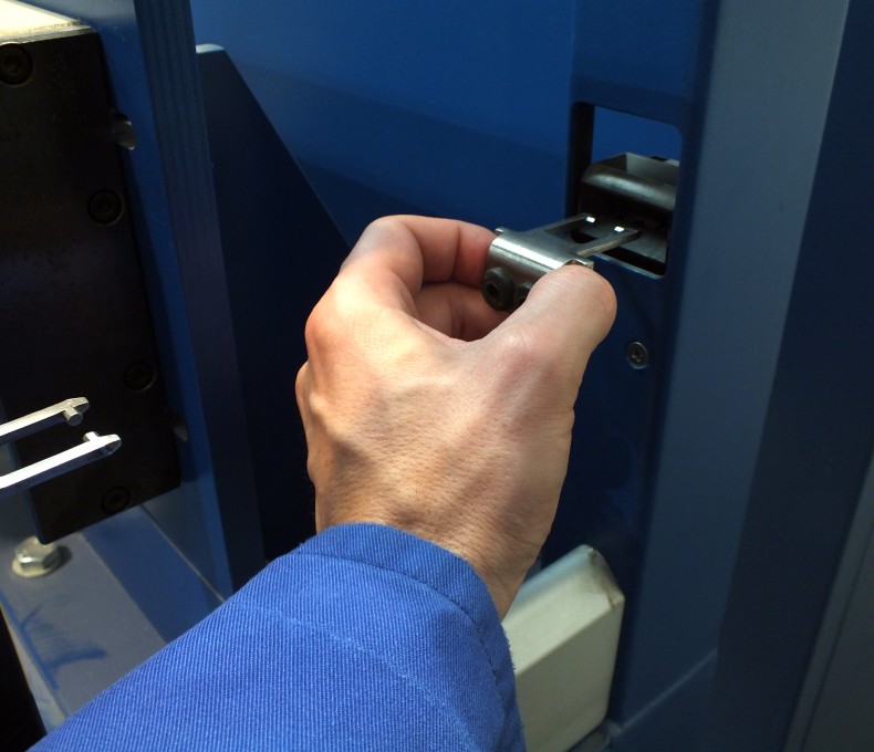 Das Bild zeigt eine menschliche Hand, die einen metallischen Gegenstand in die einen Schlitz einer Maschine schiebt. Das Bild zeigt eine menschliche Hand, die einen metallischen Gegenstand in die einen Schlitz einer Maschine schiebt.