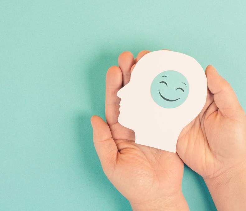 Zwei Hände halten einen ausgeschnittenen Papierkopf. Auf dem Kopf ist ein Smiley draufgeklebt. Zwei Hände halten einen ausgeschnittenen Papierkopf. Auf dem Kopf ist ein Smiley draufgeklebt.